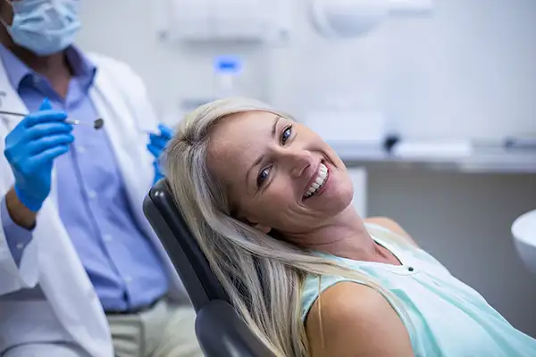 A prosthodontist checking a smiling patient in dental chair.