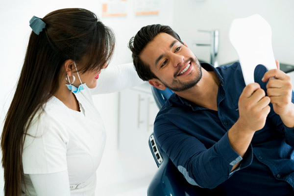 Patient looking at their new teeth with their dentist.