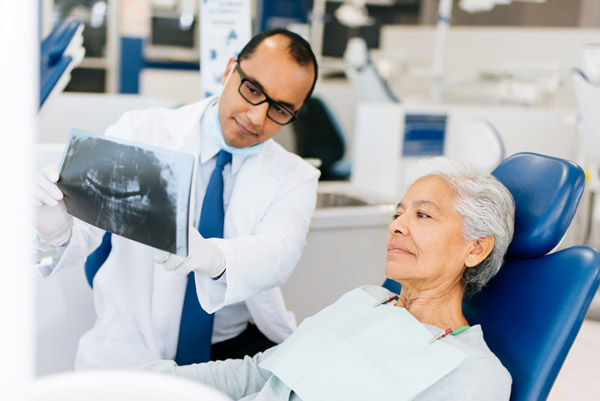 Dentist showing xray to mature woman in dental chair.