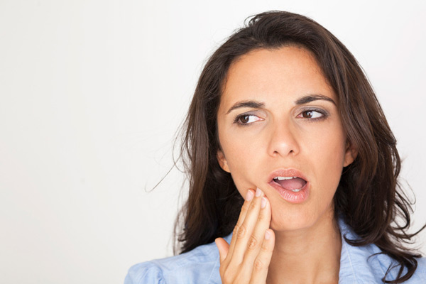 Woman holding cheek due to tooth ache.