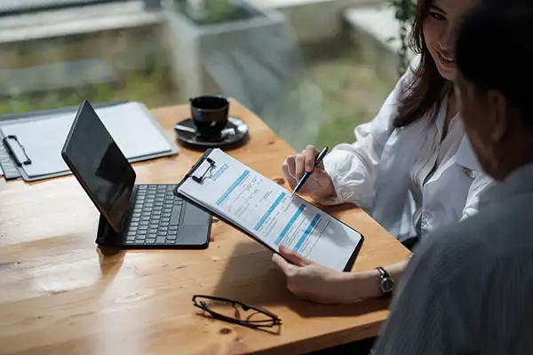 Dental Hygienist helping her patient fill out insurance paperwork on a clipboard.