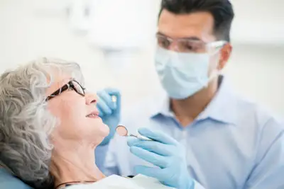 older woman sitting with dentist  chair  mirror  cleaning